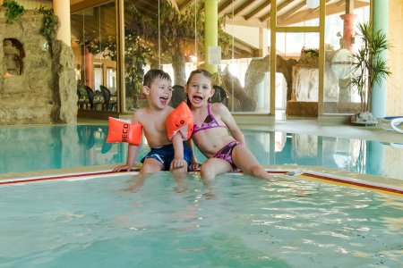 Lachende Kinder im Schwimmbad mit Schwimmflügeln.