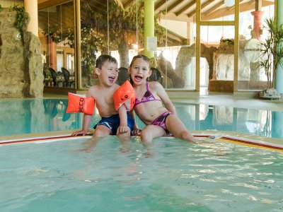 Lachende Kinder im Schwimmbad mit Schwimmflügeln.