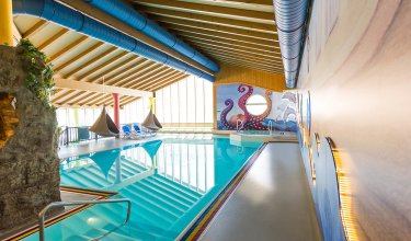 Innenansicht eines Pools mit maritimem Wanddesign und gemütlichen Hängesesseln.