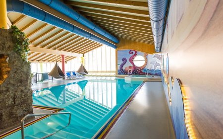 Innenansicht eines Pools mit maritimem Wanddesign und gemütlichen Hängesesseln.