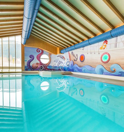 Innenansicht eines Pools mit maritimem Wanddesign, das ein Schiff und Meer darstellt.
