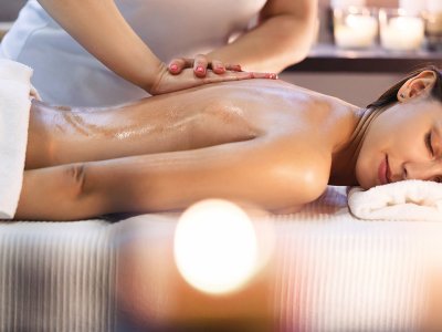 Eine Frau erhält eine entspannende Massage mit Öl, umgeben von Kerzenlicht.