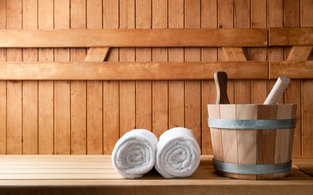 Weißer Handtuchstapel und ein Holzfass mit Holzstampfer in einer Sauna.