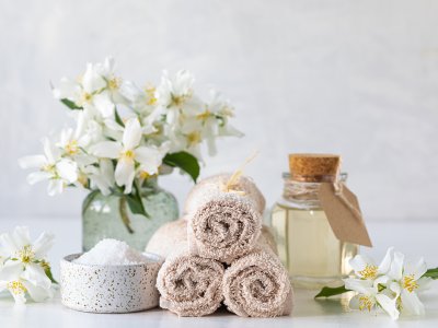 Wellness-Set mit frischen Blumen, Handtüchern, ätherischem Öl und Salz.