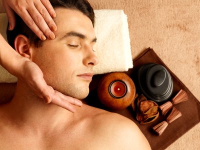 Mann erhält eine entspannende Gesichtsmassage, mit Kerze und ätherischen Ölen.