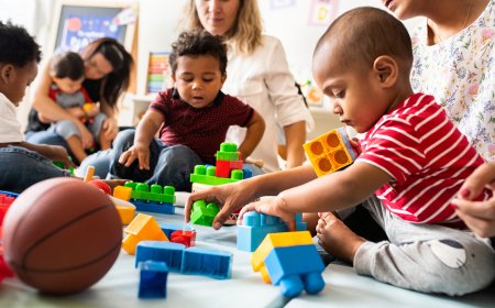 Das Bild zeigt Kinder und Erwachsene, die mit bunten Bausteinen in einem Raum spielen.