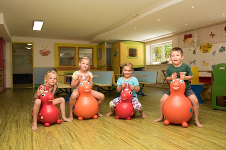 Vier Kinder sitzen auf Hüpfspielzeug, das wie Tiere aussieht.