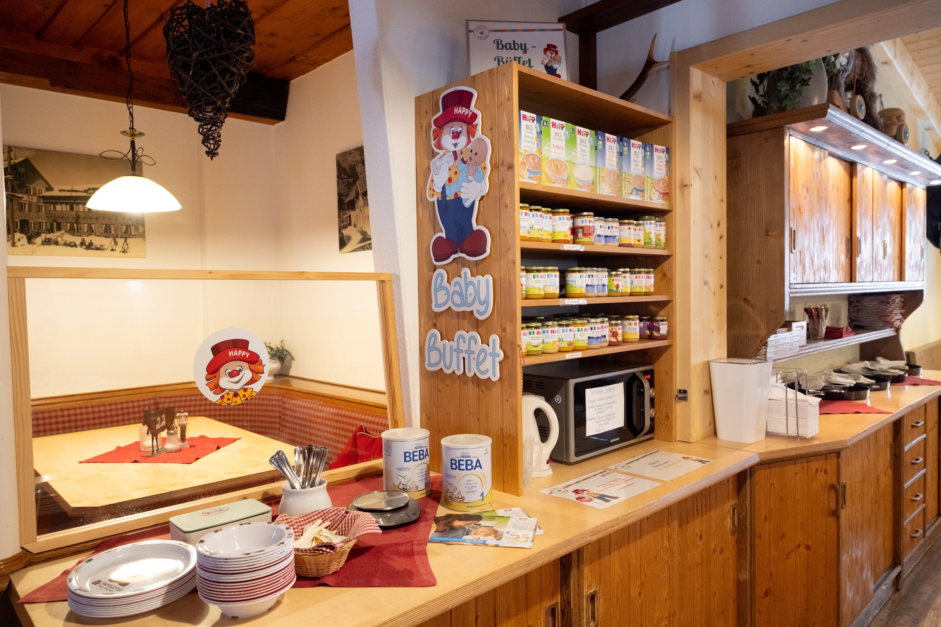 Babybuffet mit Gläschen, Milchpulver und Wärmer in gemütlicher Holzecke.   2/2