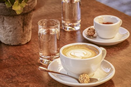 Zwei Tassen Cappuccino auf einem Tisch aus Holz.