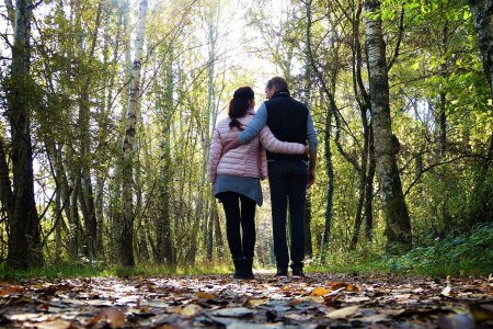 Ein Paar geht Hand in Hand durch einen Wald.