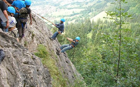 Kinder beim Abseilen an einer Felswand.