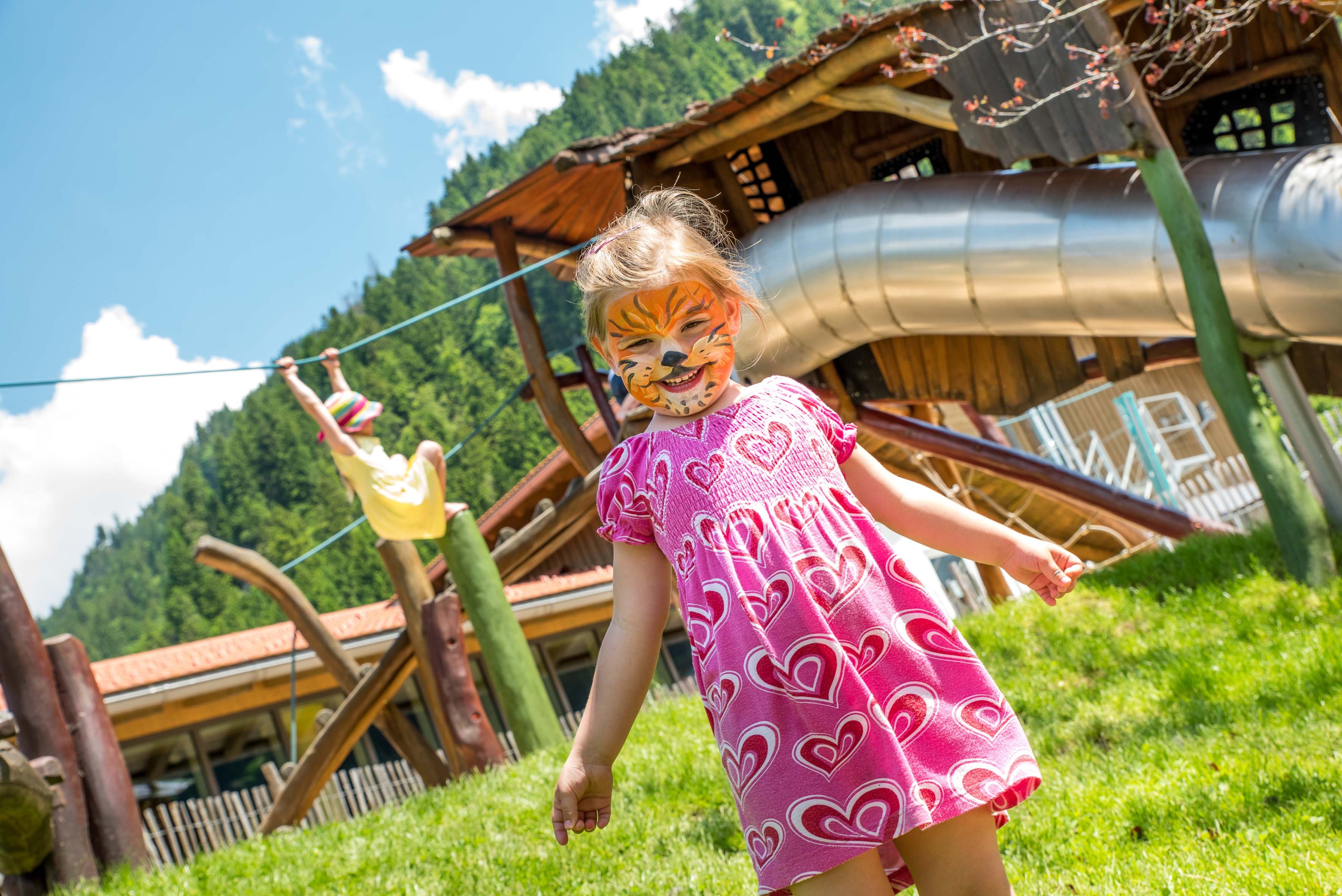 Ein Mädchen mit Löwengesichtsbemalung auf einem Spielplatz.