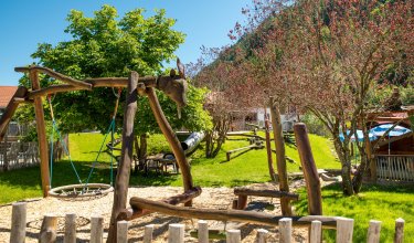 Der Spielplatz mit einem Klettergerüst, einer Rutsche und einer Schwebeschaukel.