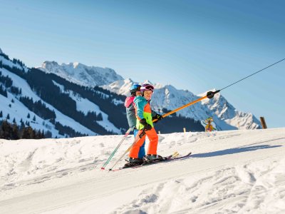 Zwei Mädchen in bunten Skianzügen fahren mit dem Skilift.