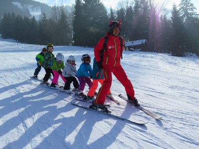 Zwei Kinder im Schnee beim Spielen auf einem blauen Reifenkarussell