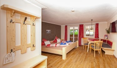 Großzügiges Doppelzimmer mit Garderobe, Sitzecke und Balkon.