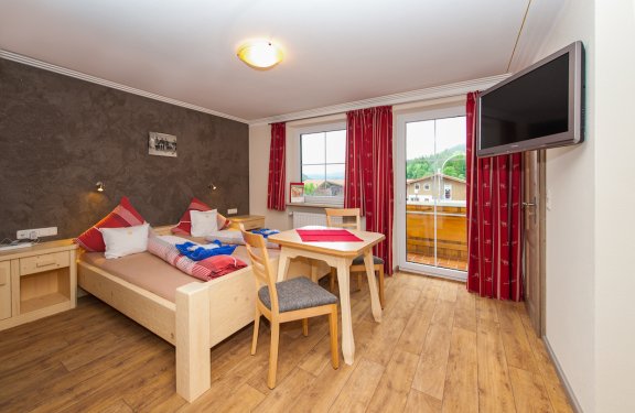Doppelzimmer mit Tisch und Zwei Stühlen, TV und Balkon.