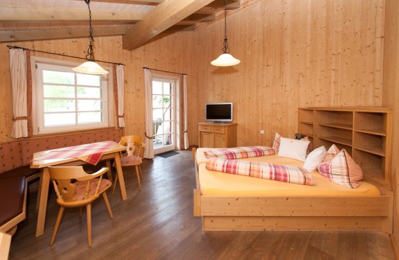 Doppelzimmer komplett aus Holz, mit gemütlicher Sitzecke und Balkon.