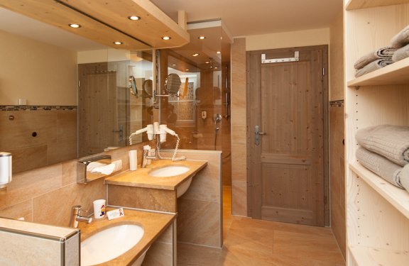 Badezimmer mit mediterranen Fliesen, zwei Waschbecken und einer Dusche mit Glaswand.