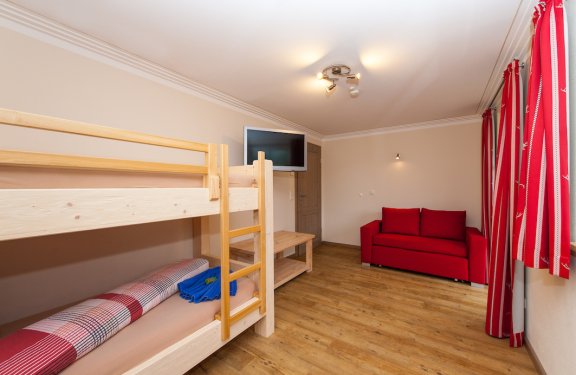 Kinderzimmer mit Stockbett, Sofa und Fernseher.