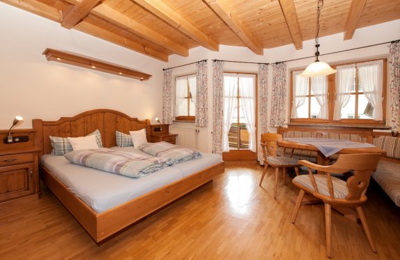 Doppelzimmer mit Sitzecke, Balkon und sehr viel Holzarbeit.