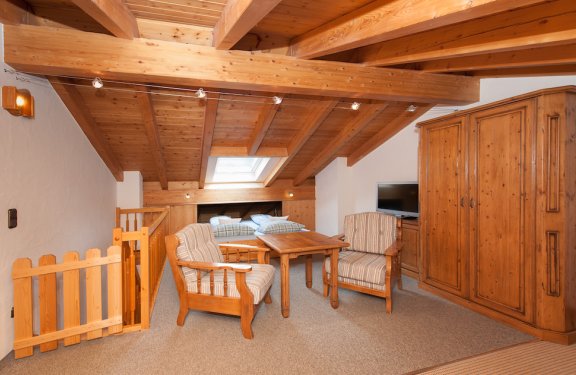 Schlafzimmer mit Doppelbett, zwei Stühlen mit Tisch, Schrank und Decke aus Holz mit Dachfenster.
