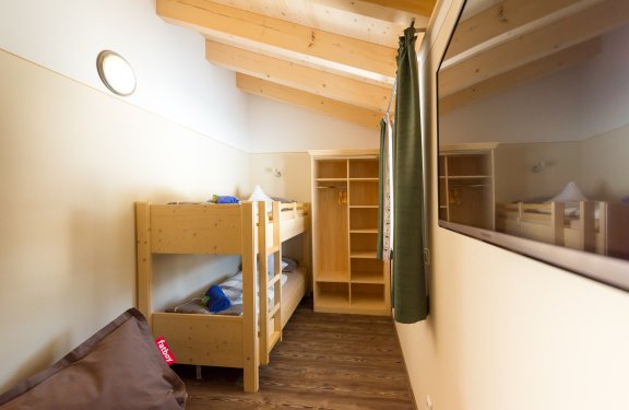Helles Kinderzimmer mit Stockbett, Kasten und Sitzsack.