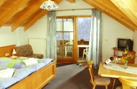 Doppelzimmer mit Tisch mit Stühlen, Sofasessel und Balkon.