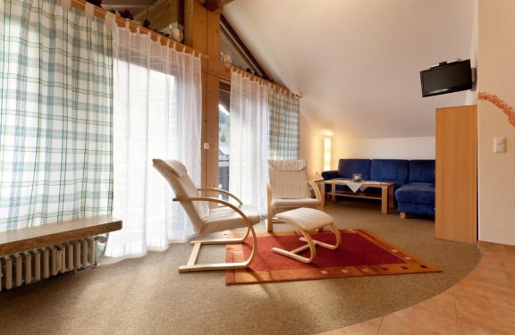 Wohnzimmer mit zwei bequemen Stühlen, Sofa und Balkon.