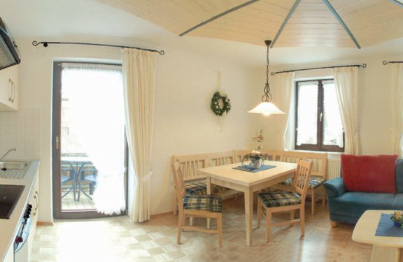 Heller Wohnbereich mit Küchenzeile, Sitzecke, Sofa und Balkon.