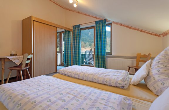 Zimmer mit Doppelbett, Schreibtisch, Schrank und Balkon.